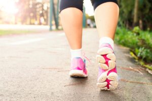 Close-up of legs in trainers walking on pavement, illustrating staying active during commute and workplace wellbeing
